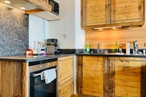 a kitchen with wooden cabinets and a stove at #AH15 Les Chalets d'Ysalis in LʼHuez +13 photos