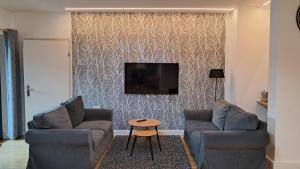 a living room with two chairs and a tv on a wall at Apartmenthaus Hinterer in Bad Goisern