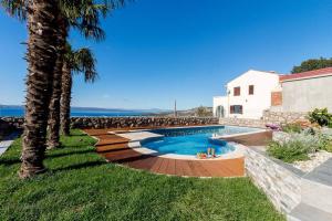 einen Pool im Garten mit Palmen in der Unterkunft Villa IL K in Klenovica