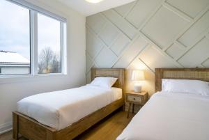 two beds in a room with a window at The Luxury Black Rose Chalet at The Blue Mountains for 20 in Blue Mountains