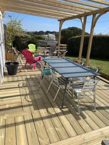 a picnic table and chairs on a wooden deck at Grande maison à 200m de la plage in Plouguerneau