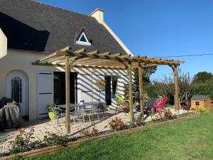 a wooden pergola with a table and chairs in a yard at Grande maison à 200m de la plage in Plouguerneau