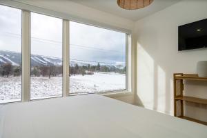 a bedroom with a large window with a snowy mountain view at White Rose Chalet at Blue Mountains for 20 w Hot Tub in Blue Mountains +54 photos