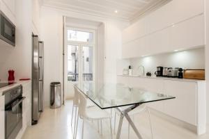 リスボンにあるFLH Downtown Modern Flatの白いキッチン(ガラステーブル、白い椅子付)