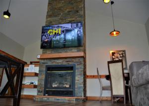 a living room with a fireplace with a flat screen tv at The Blue Mountains Chalet for 20- 8BR Bliss w Hot Tub in Blue Mountains