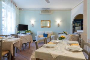 a dining room with tables and chairs and a tv at Hotel Eden in Arenzano