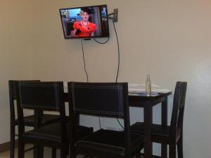 a dining room table with two chairs and a tv on the wall at Chateau Elysee in Manila