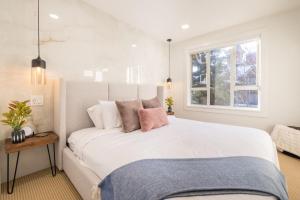 a bedroom with a large white bed and a window at Whistler Village 2BR, Sleeps 6, Air Con, Free Parking in Whistler
