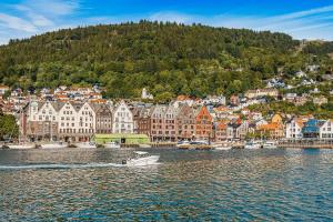 a boat in the water in front of a city at Dinbnb Apartments I Charming 3-Bedroom in the Heart of the City in Bergen