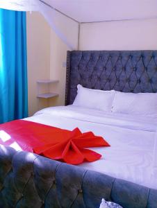 a red bow laying on a white bed at Vee's 1br Apartment at Lower Section 58 with Lakeviews in Nakuru +19 photos