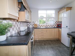 Una cocina con gabinetes de madera y un refrigerador blanco. en Woodside Guest House, en Coleraine