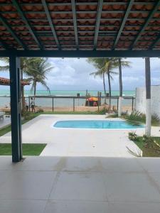 a swimming pool with the beach in the background at Casa beira-mar 25km do aeroporto de Recife in Cabo de Santo Agostinho
