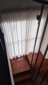 a window with a white curtain and a wooden floor at Serendipia Santa Ana in Santa Ana