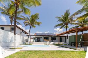 a house with a swimming pool and palm trees at Casa beira-mar 25km do aeroporto de Recife in Cabo de Santo Agostinho