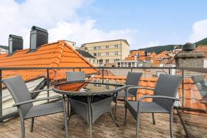 a patio with chairs and a table on a balcony at Dinbnb Apartments I Historical Two-Floor Apartment with Rooftop Panorama I 1645 Heritage in Bergen