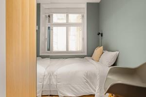 a bedroom with a white bed with a window at Dinbnb Apartments I 500m to Bryggen in Bergen