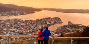 a man and a woman standing on a ledge overlooking a city at Dinbnb Apartments I 500m to Bryggen in Bergen