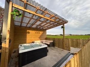 a hot tub sitting under a wooden pergola at Loughbracken Lodge in Pomeroy