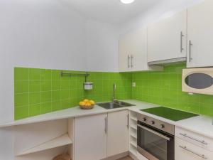 a kitchen with white cabinets and green tiles at Apartment Marinada by Interhome in Tossa de Mar
