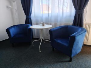 two blue chairs and a table in a room at Harmonica Studio in Nowy Sącz