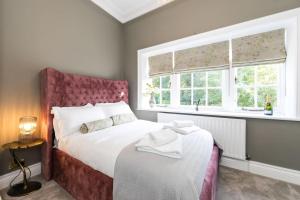 a bedroom with a bed with a pink headboard and two windows at Hillthorpe Estate - 14 Bed Manor House with Hot Tubs and Secluded Gardens in East Hardwick