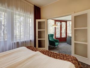 a bedroom with a bed and a chair and a mirror at Narva-Jõesuu Medical Spa in Narva-Jõesuu