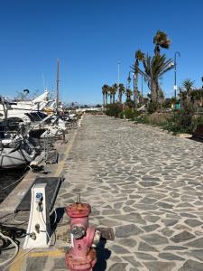 a red fire hydrant on a sidewalk next to boats at B&B op een zeiljacht aan de Costa Blanca in Guardamar del Segura