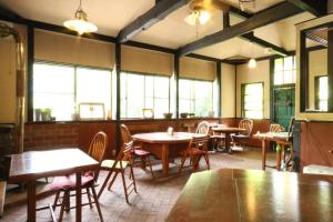 a dining room with tables and chairs and windows at Flower Garden in Takamori
