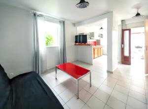 un salon avec une table rouge et une cuisine dans l'établissement Maison charmante à Sainte-Anne avec piscine partagée., à Sainte-Anne 12 autres photos