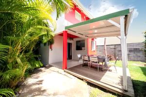 une maison avec une terrasse avec une table et des chaises dans l'établissement Maison charmante à Sainte-Anne avec piscine partagée., à Sainte-Anne