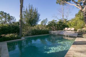 a swimming pool in a yard with two chairs in it at Villa Canadell con Parking Piscina y Barbacoa - WeHost Costa Brava in Calella de Palafrugell