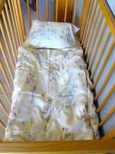 a bed in a crib with a blanket on it at Humlehjarta family room, 3 separate beds in Överkalix