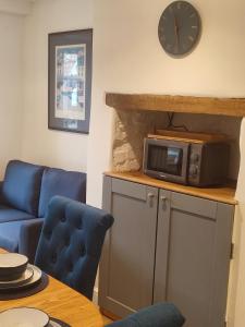 a living room with a blue couch and a microwave at Dartmouth Diddy House in Dartmouth