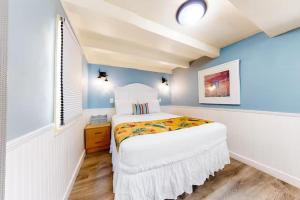 una piccola camera da letto con un letto bianco e pareti blu di Welcome Matt's - Truman @ Duval Unit B a Key West