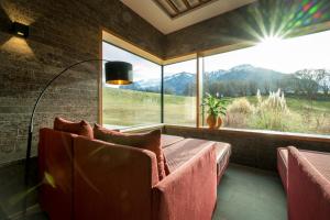 a living room with a couch and a large window at Klosterhof – Alpine Hideaway & Spa in Bad Reichenhall