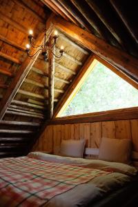 ein Schlafzimmer in einem Blockhaus mit einem großen Fenster in der Unterkunft Gaismas klēts in Upmaļciems