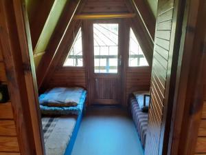 ein Dachzimmer mit zwei Fenstern und einer Couch in der Unterkunft Domki nad jeziorem i pod lasem in Zdbice