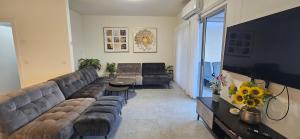 a living room with a large couch and a television at וילה מינרל villa mineral in Neve Zohar
