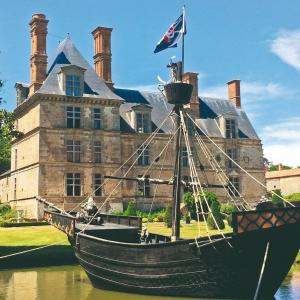 un barco en el agua frente a un castillo en Camping maeva Respire Parfums d'Eté, en Jard-sur-Mer