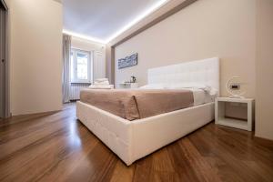 a white bedroom with a large bed and wooden floors at Le stanze sui musei vaticani in Rome