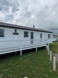 a white house with a porch and a fence at Clearwater Lodge - 392 Valencia Heights in Greatstone
