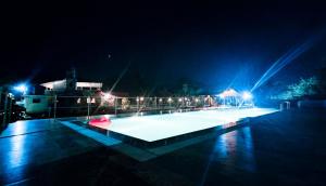 a lit up swimming pool at night with lights at Paradise Farm Alibaug in Bhāweghar