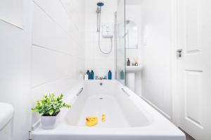 a white bathroom with a tub and a sink at Cosy Royal Blue 3-Bedroom Family Home Sleeps 6, Free Parking & Wi-Fi, Garden and Private Patio in Leicester