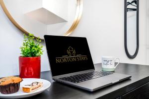 a laptop computer sitting on a desk with a plate of food at Cosy Royal Blue 3-Bedroom Family Home Sleeps 6, Free Parking & Wi-Fi, Garden and Private Patio in Leicester +36 photos