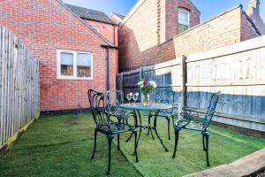 a table and chairs on a yard with a fence at Cosy Royal Blue 3-Bedroom Family Home Sleeps 6, Free Parking & Wi-Fi, Garden and Private Patio in Leicester