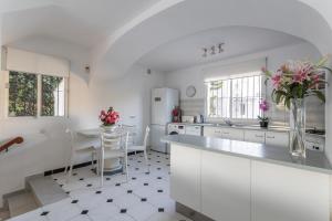 a white kitchen with a table and a vase of flowers at Villa Nerja in Nerja