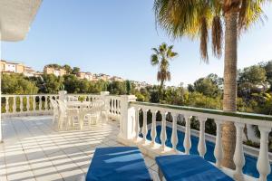 a balcony with chairs and a table and palm trees at Villa Nerja in Nerja