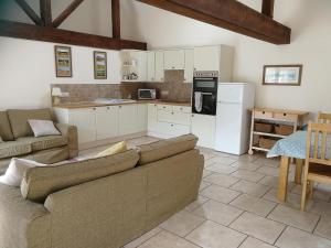 a living room with a couch and a kitchen at Dovehouse Farm Barns in Kingsey
