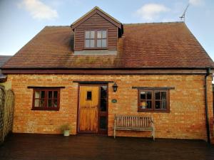 a brick house with a wooden door and a bench at Dovehouse Farm Barns in Kingsey