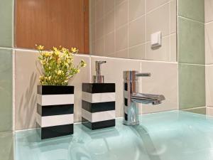 a bathroom sink with a faucet and a vase of flowers at APF Beach T2 Cabanas Home by Junto ao Mar in Cabanas de Tavira